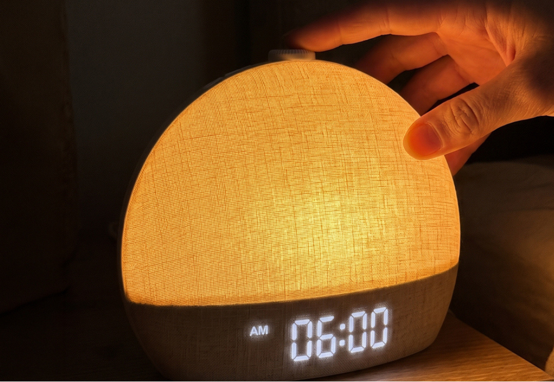 Hand pressing the top button of the Salutive sunrise alarm clock